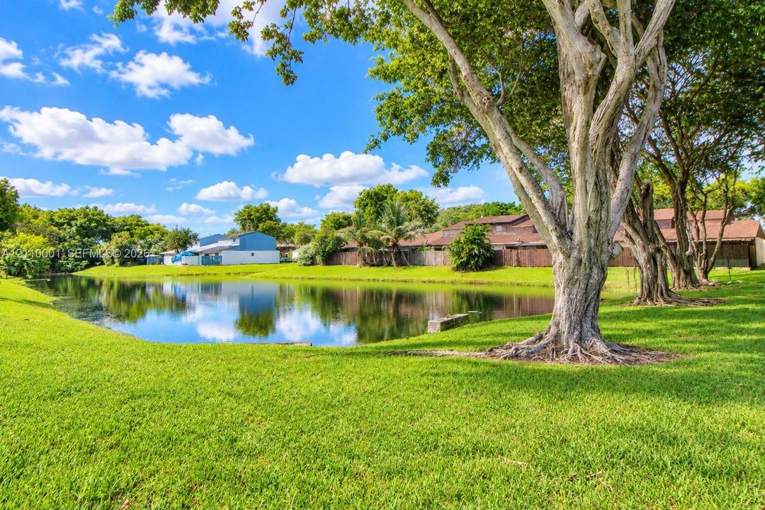 Waterfront lot featuring a manicured lawn, mature shade trees, and perimeter privacy fencing