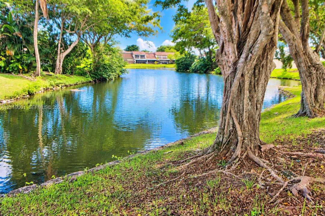 Waterfront lot featuring a natural pond, mature trees, and landscaped lawn