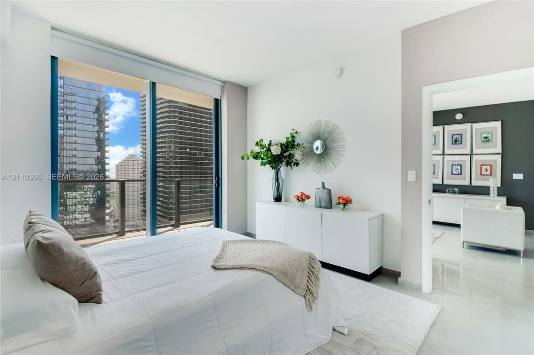 Floor-to-ceiling windows featuring urban scenery, sliding glass door with balcony access, and polished stone flooring