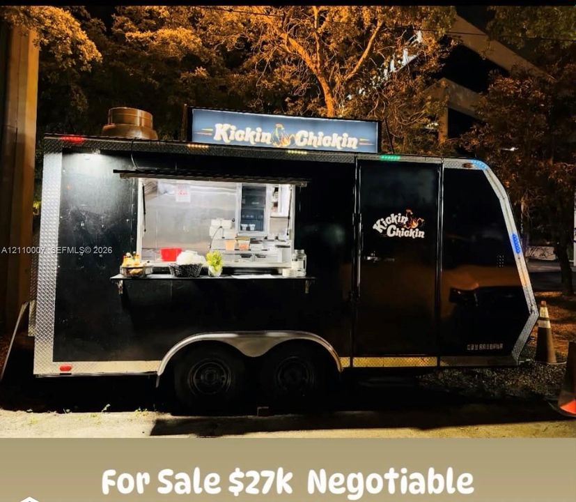 Mobile catering trailer featuring a black exterior finish, dual-axle chassis, service window with fold-down counter, and top-mounted illuminated signage