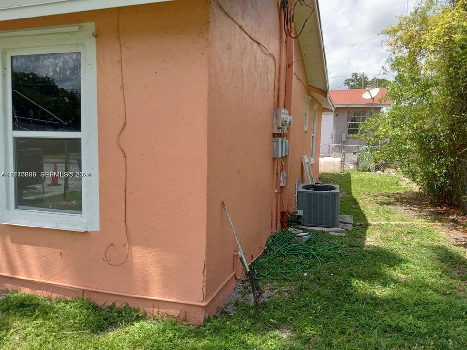 Stucco exterior featuring a single-hung window with white casing and an exterior-mounted central air conditioning condenser unit