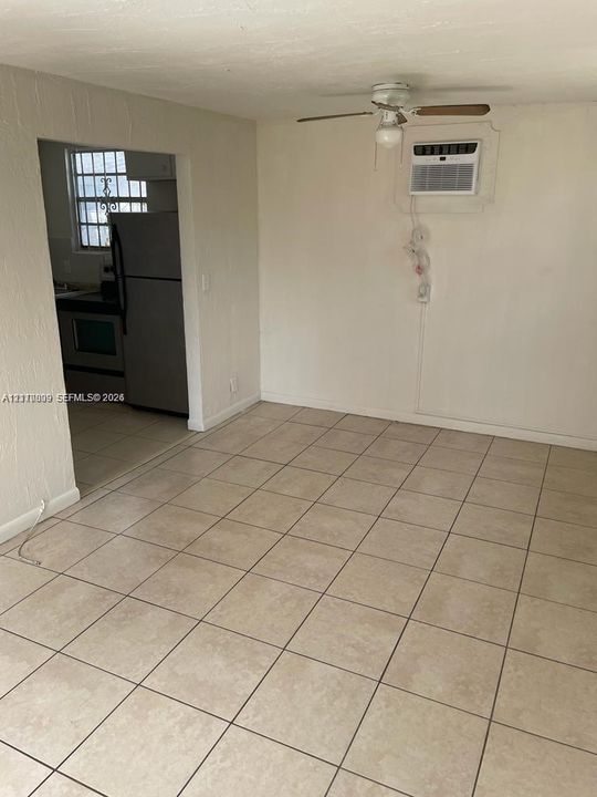 Neutral-toned tile flooring, ceiling-mounted fan, and wall-mounted air conditioning unit