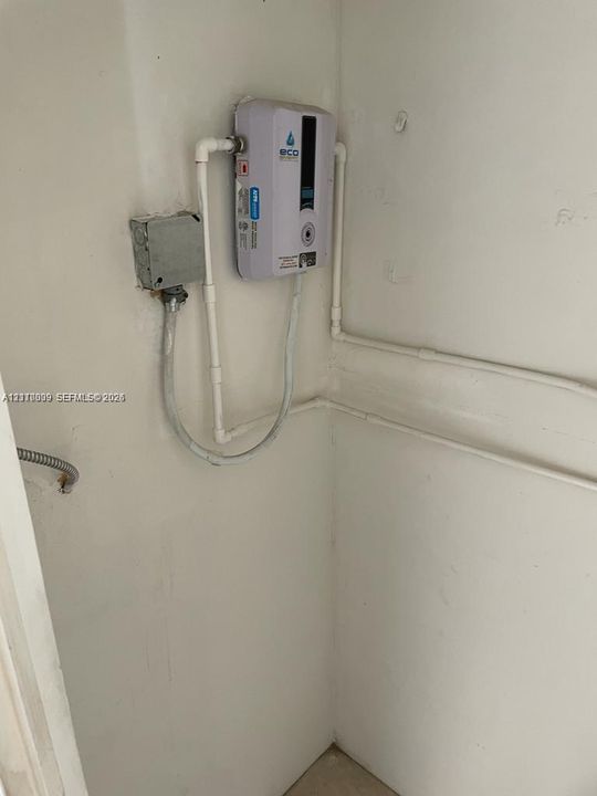 Tankless electric water heater featuring a digital temperature display, wall-mounted unit, and dedicated electrical conduit housing