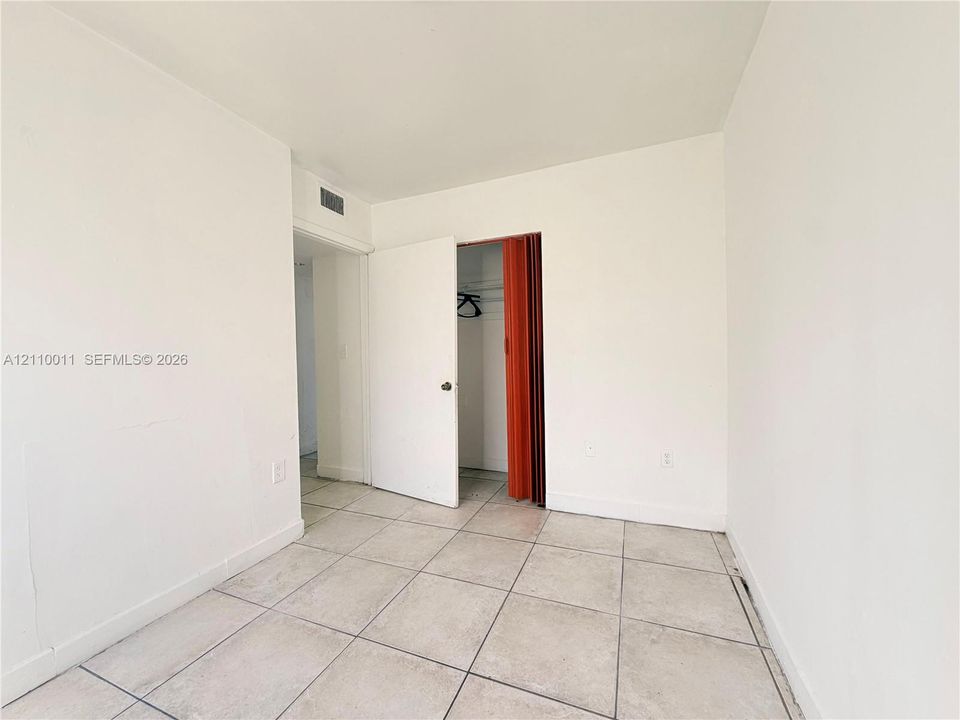Neutral interior space featuring ceramic tile flooring, solid-core interior doors, and a built-in closet with an accordion-style door