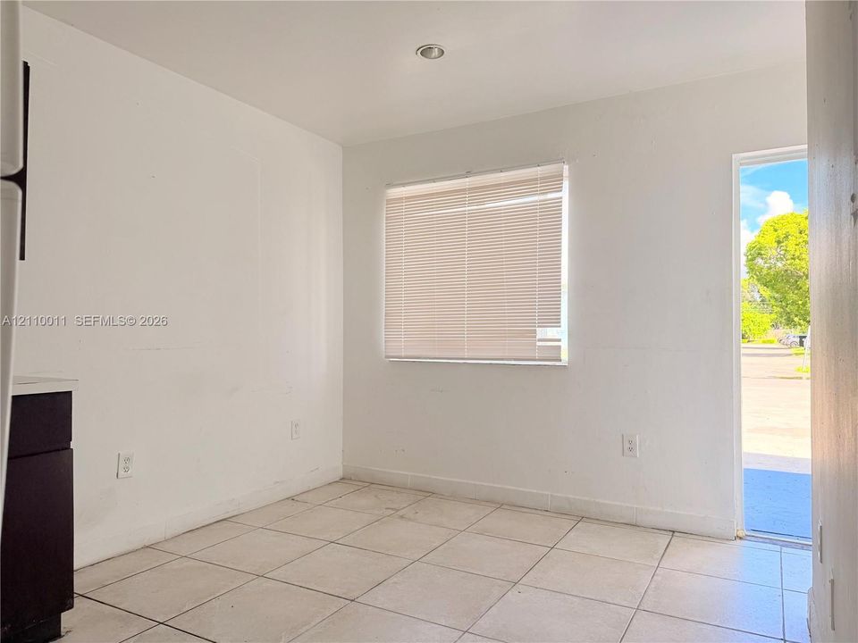 Interior space featuring large-format neutral floor tile, recessed ceiling lighting, and a window with horizontal blinds