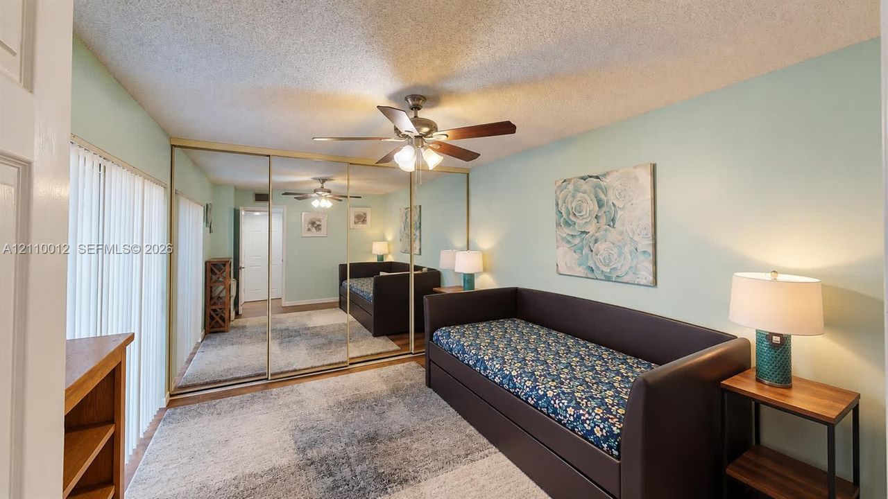 Room featuring mirrored closet doors, a ceiling fan with integrated lighting, and vertical window blinds