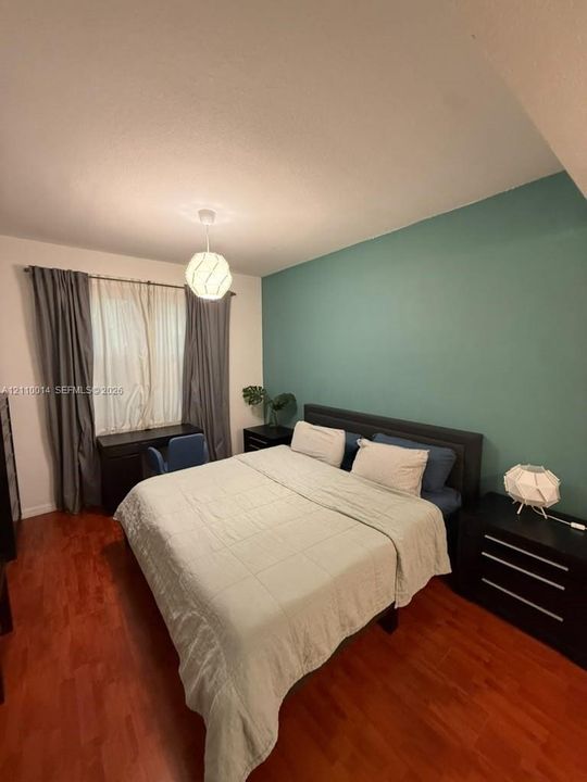 Wood-finish flooring, accent wall, and geometric pendant lighting