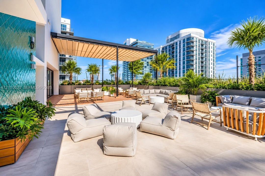 Outdoor terrace featuring large-format tile flooring, a structured pergola, and a decorative textured accent wall