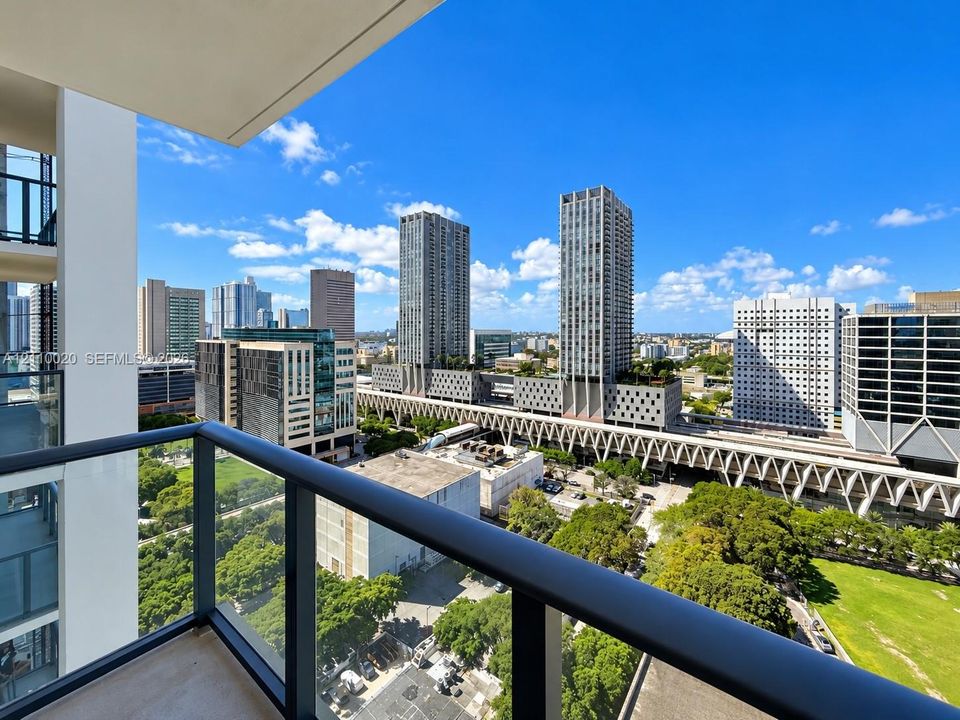 Private balcony featuring a dark metal railing and glass panel inserts, providing an elevated urban landscape perspective