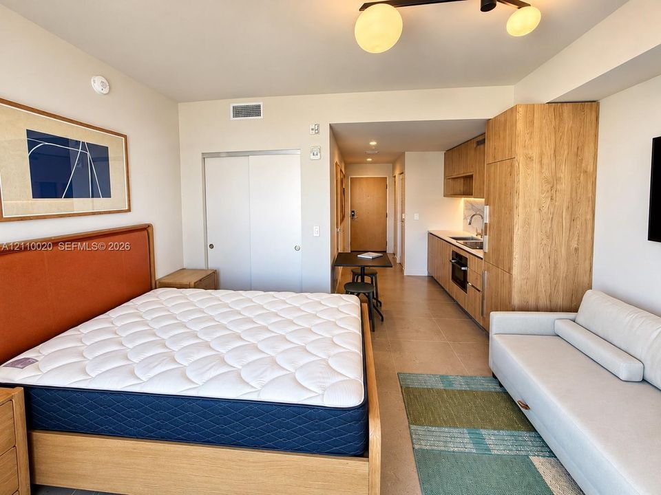 Studio space featuring wood-finish cabinetry, built-in kitchen appliances, and polished tile flooring