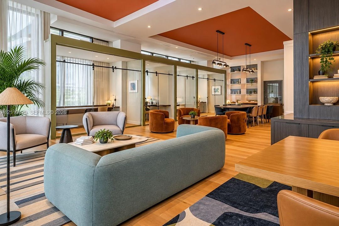 Open-concept common area featuring wood-finish flooring, recessed tray ceilings with accent color, floor-to-ceiling glass-paneled partition walls with sliding hardware, and custom built-in floor-to-ceiling shelving with integrated lighting