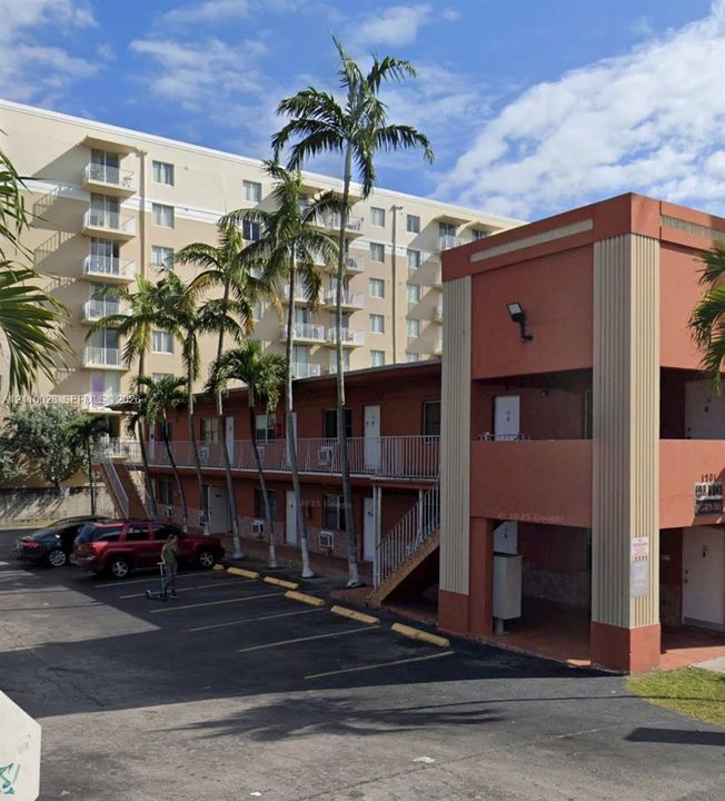 Two-story exterior with stucco finish, integrated outdoor staircase, metal railings, and dedicated asphalt parking