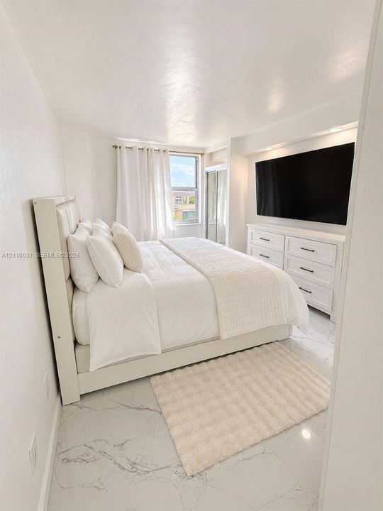 Large-format white tile flooring with grey veining, recessed lighting, and a floor-to-ceiling mirrored closet door