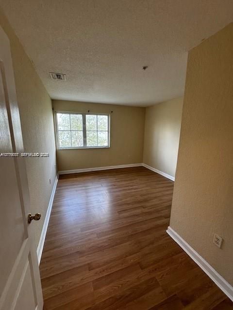Room featuring wood-finish flooring, textured walls, and a multi-pane window
