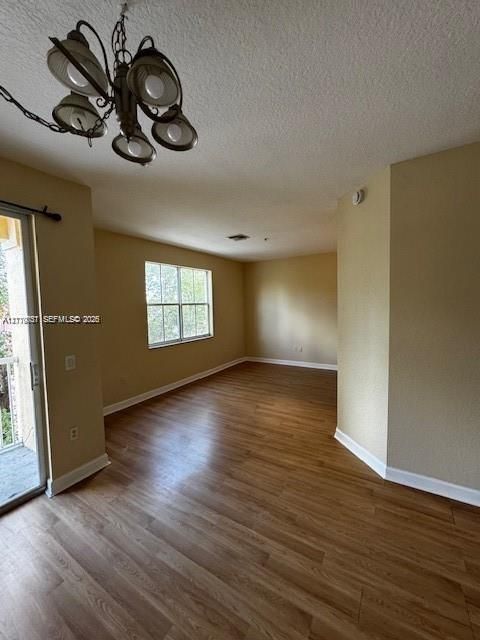 Interior space featuring wood-finish flooring, a multi-arm overhead light fixture, glass sliding doors, and a double-pane window