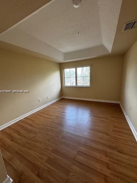 Tray ceiling, wood-finish flooring, and multi-pane window with natural light