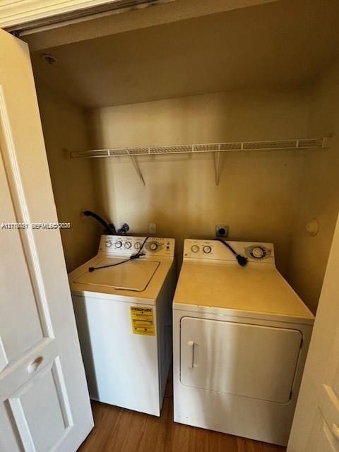 Dedicated laundry closet featuring a built-in wire shelving unit, wood-finish flooring, and dual bi-fold doors