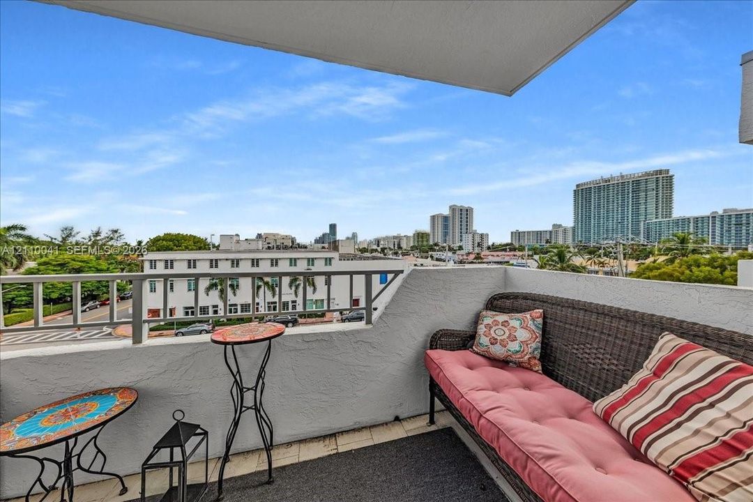 Private balcony featuring textured stucco walls, metal railings, and tiled flooring with an urban cityscape backdrop