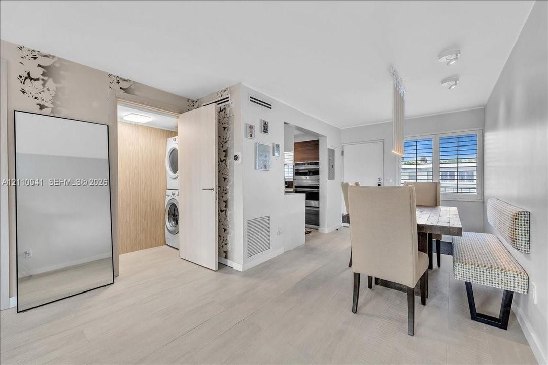 Light-toned wood-finish flooring, dedicated laundry closet with stackable appliances, recessed ceiling lighting, and windows with horizontal blinds