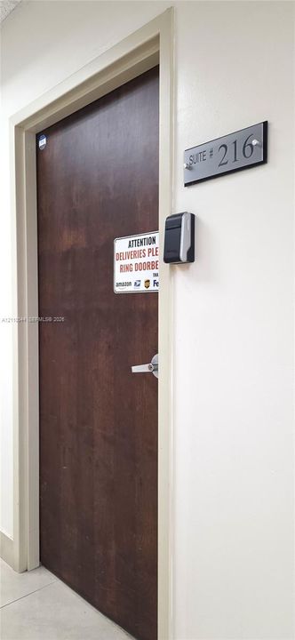 Solid-core wood-finish door accented by a suite number placard