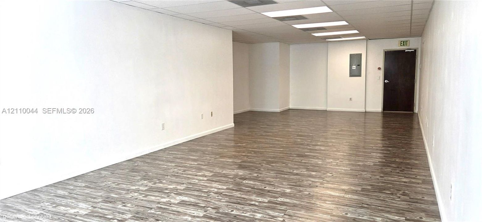 Open floor plan featuring neutral walls, wood-finish flooring, recessed lighting, and a single-panel door