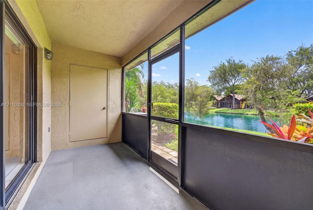 Screened-in patio featuring a concrete floor, a metal-framed enclosure with a screen door, and exterior storage closet access