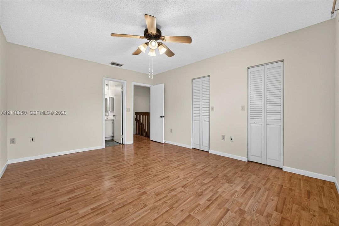 Wood-finish flooring, dual bi-fold closet doors, and ceiling fan with integrated lighting fixture