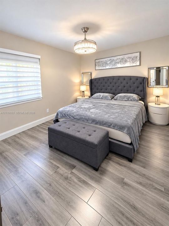 Hallway featuring wood-finish flooring, dual sets of white louvered-door closets, and recessed lighting