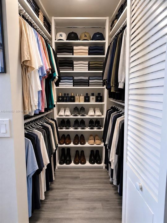 Closet featuring custom white built-in cabinetry, three soft-close storage drawers, adjustable open shelving, dual hanging rods, and white louvered bifold doors over wood-finish flooring