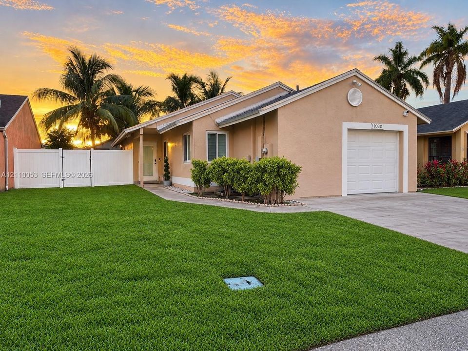 Single-story residence featuring a stucco exterior, an attached one-car garage, a concrete driveway, and a white vinyl privacy fence