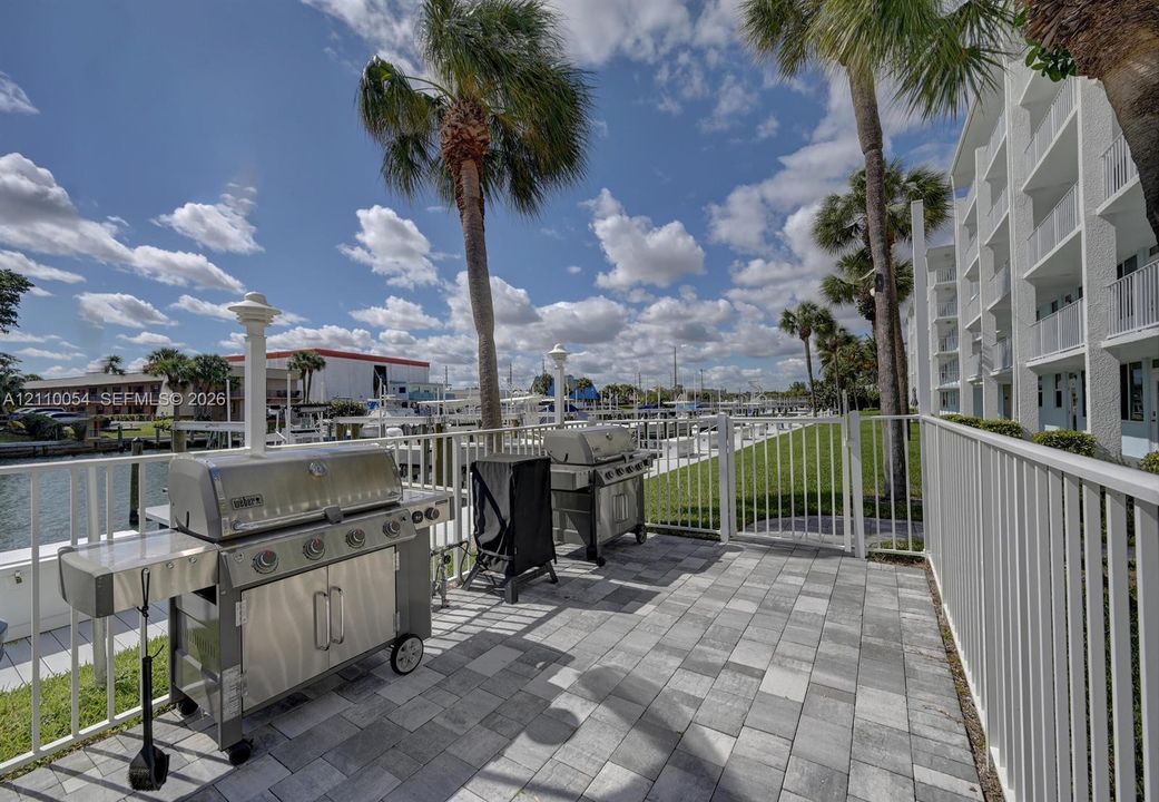 Waterfront patio featuring stone-paver flooring, metal safety fencing, and direct access to marina boat slips