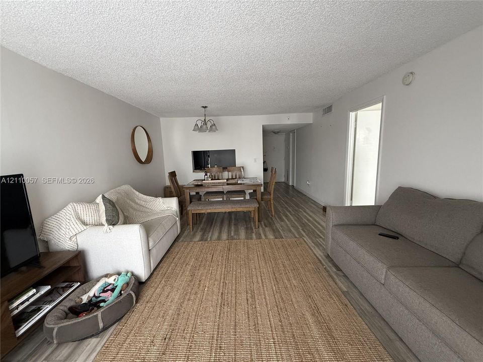 Open-concept floor plan featuring wood-finish flooring, textured ceiling, and a built-in kitchen pass-through window
