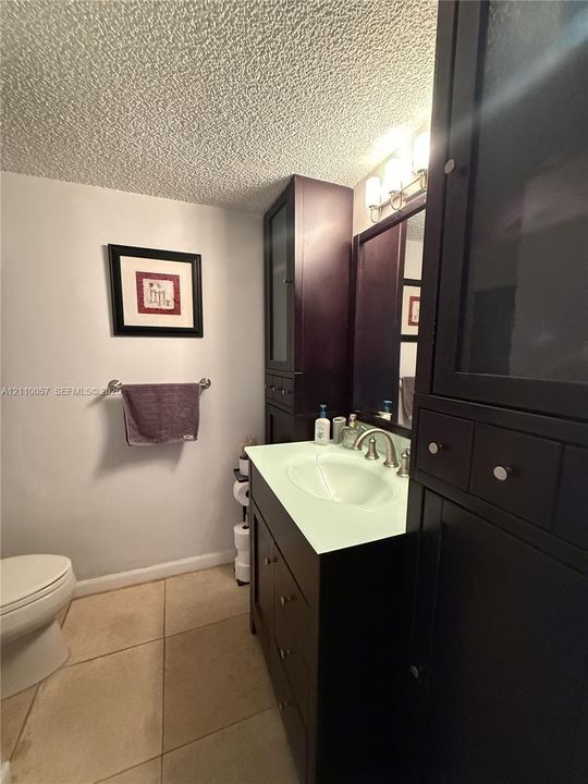 Vanity featuring dark-toned cabinetry, an integrated sink, polished metal faucet, and tall flanking storage cabinets with glass-panel doors