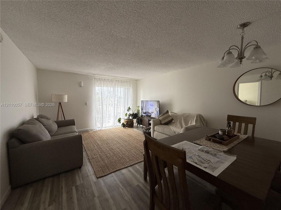 Living area featuring wood-finish flooring, sliding glass doors, and a multi-light chandelier