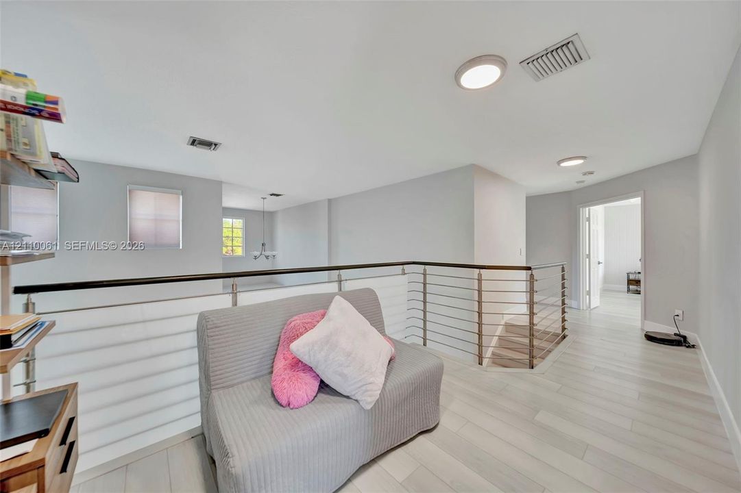 Open area featuring wood-finish flooring, metal cable railing, and recessed ceiling lighting