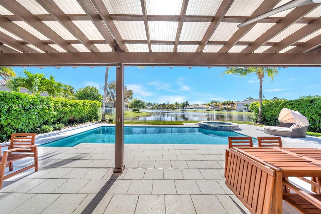 Covered outdoor patio featuring a pergola, swimming pool with integrated spa, paved pool deck, and perimeter fencing