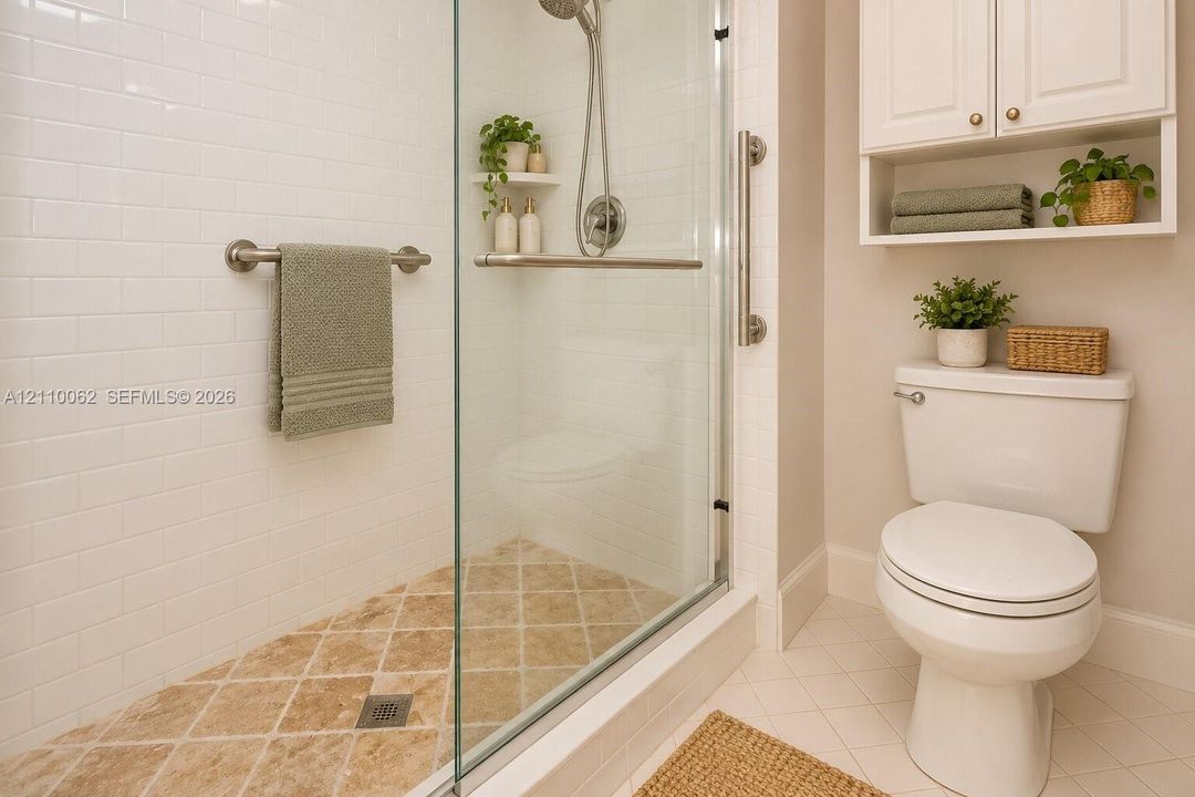 Walk-in shower with white subway tile surround, diamond-patterned stone flooring, clear glass enclosure, and mounted grab bars, accompanied by white built-in cabinetry and a standard-height toilet