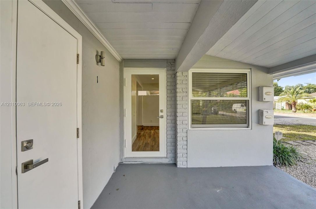 Covered entryway featuring a glass-panel entry door, brick exterior accents, dual wall-mounted mailboxes, and an external light fixture