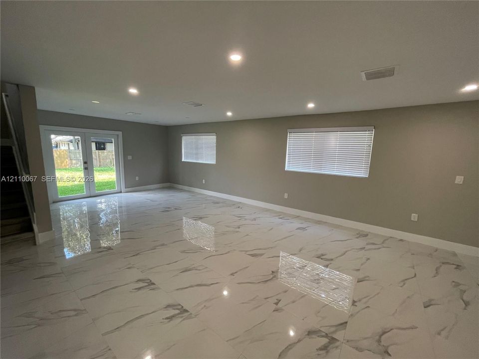 Open interior space featuring polished stone-finish tile flooring, recessed ceiling lighting, and double glass-paned doors