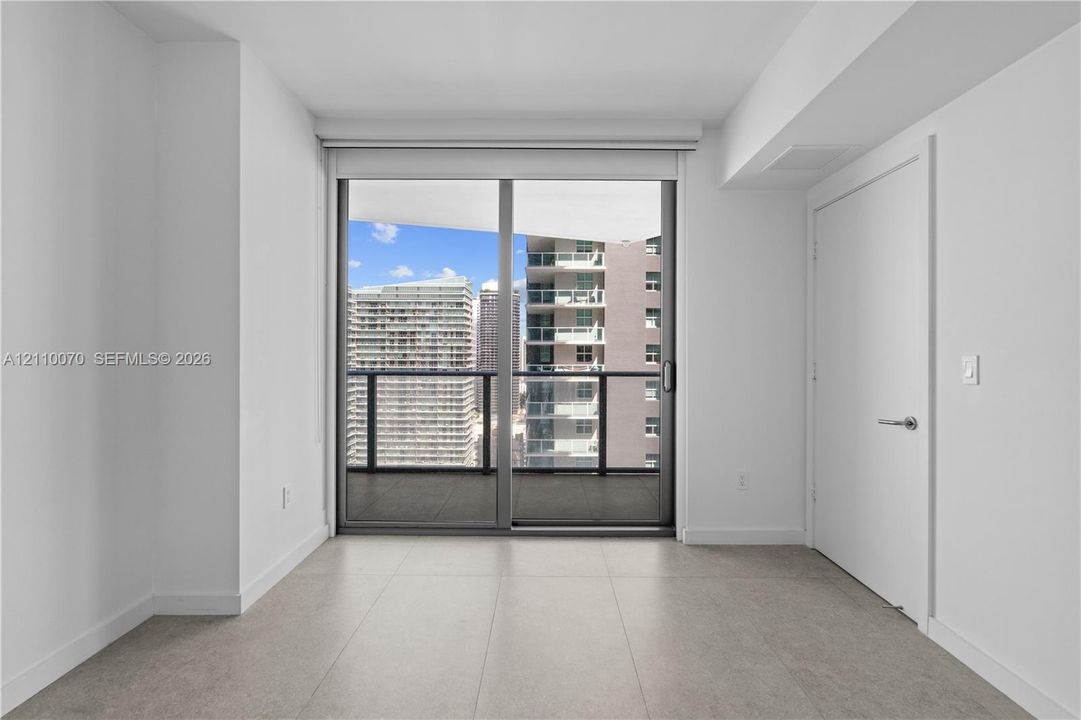 Large-format ceramic floor tiling, full-height glass sliding door, private balcony with metal railing, and neutral wall finishes