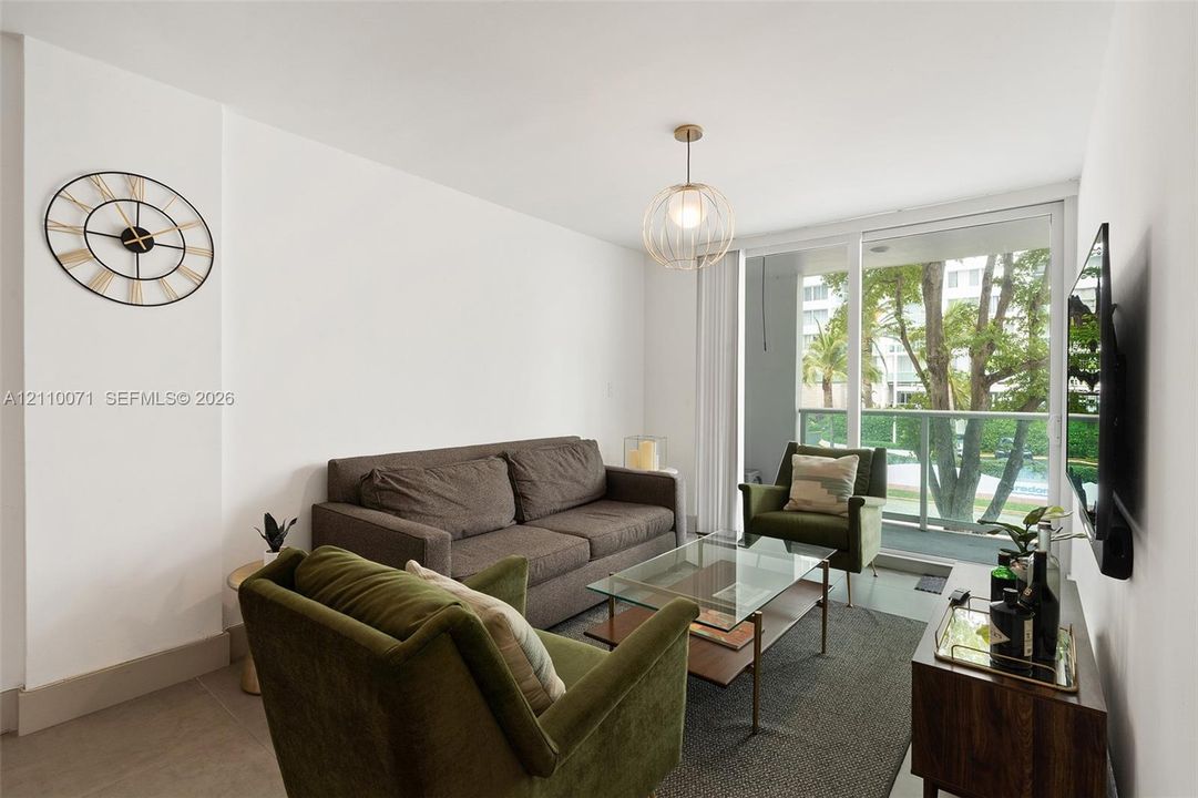 Interior space featuring floor-to-ceiling glass sliding doors, a metal-frame balcony railing, polished neutral flooring, and a contemporary spherical pendant light