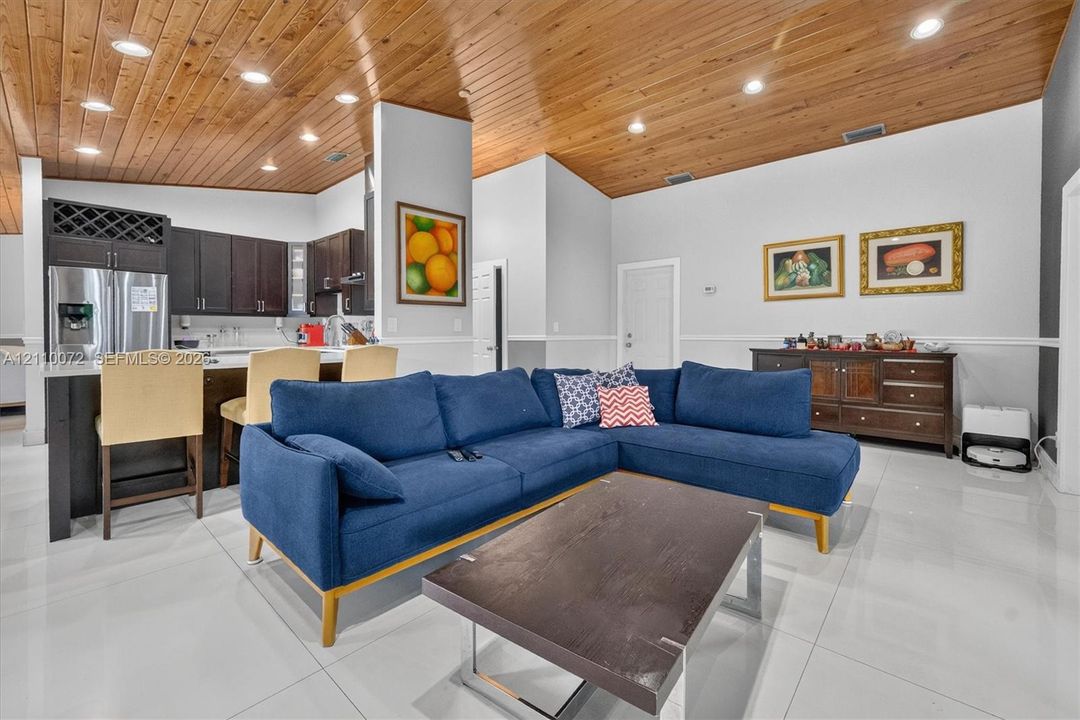 Vaulted tongue-and-groove wood ceiling featuring recessed lighting, polished porcelain tile flooring, and dark-toned cabinetry with integrated wine storage