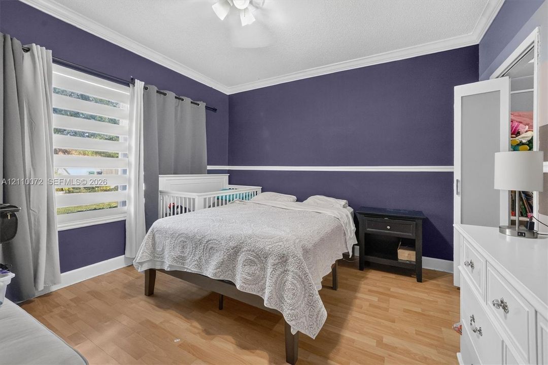 Room featuring wood-finish flooring, crown molding, chair rail trim, and horizontal window blinds