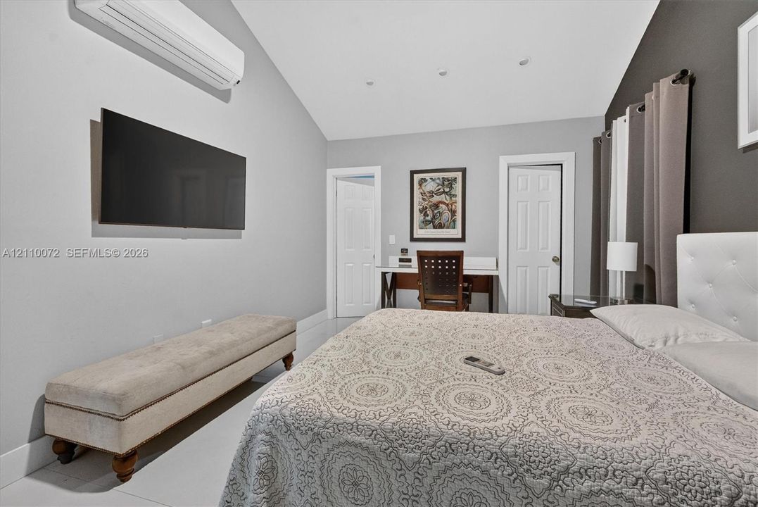 Vaulted ceiling featuring recessed lighting, wall-mounted ductless climate control unit, and crisp white tile flooring