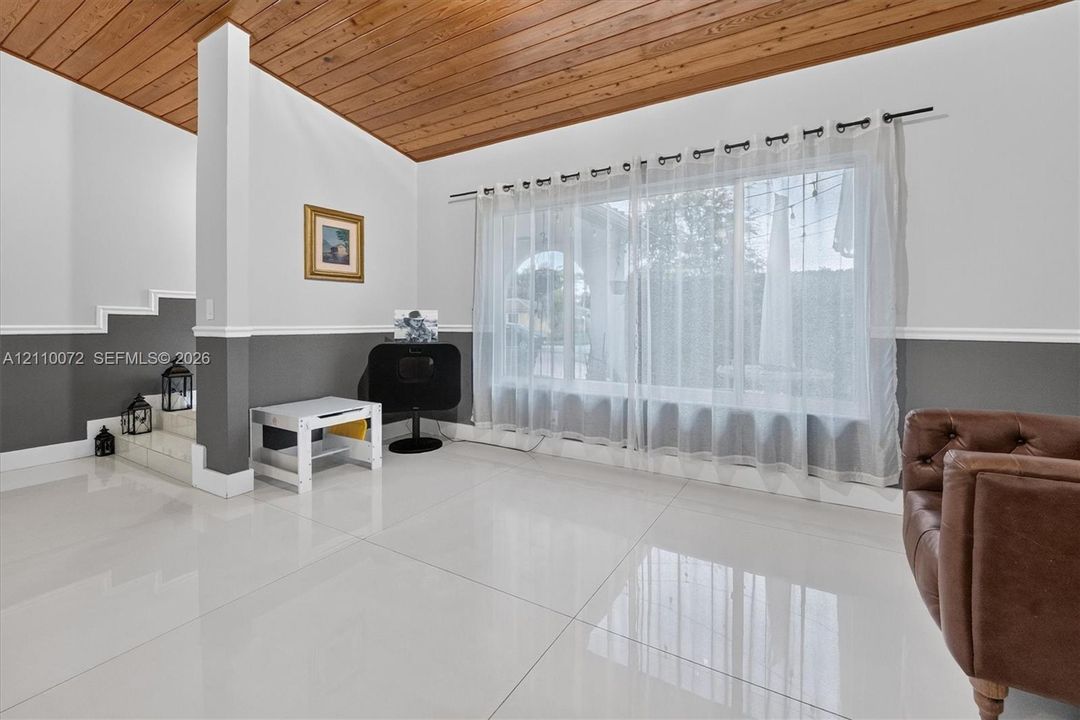 Vaulted wood-plank ceiling, large-format tile flooring, and dual-tone wall treatment with chair rail molding