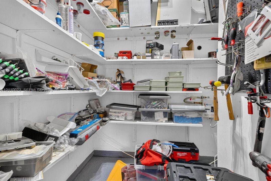Storage area featuring white tiered shelving and a wall-mounted pegboard system