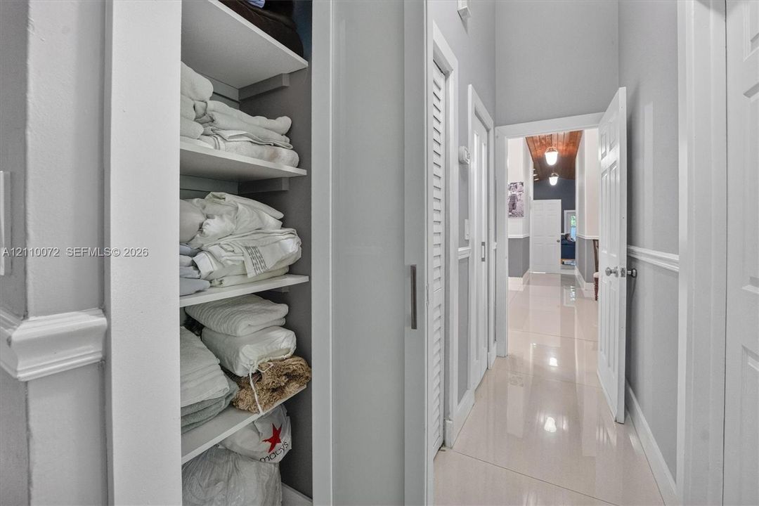 Built-in floor-to-ceiling shelving, crisp white louvered doors, polished tile flooring, and chair rail molding