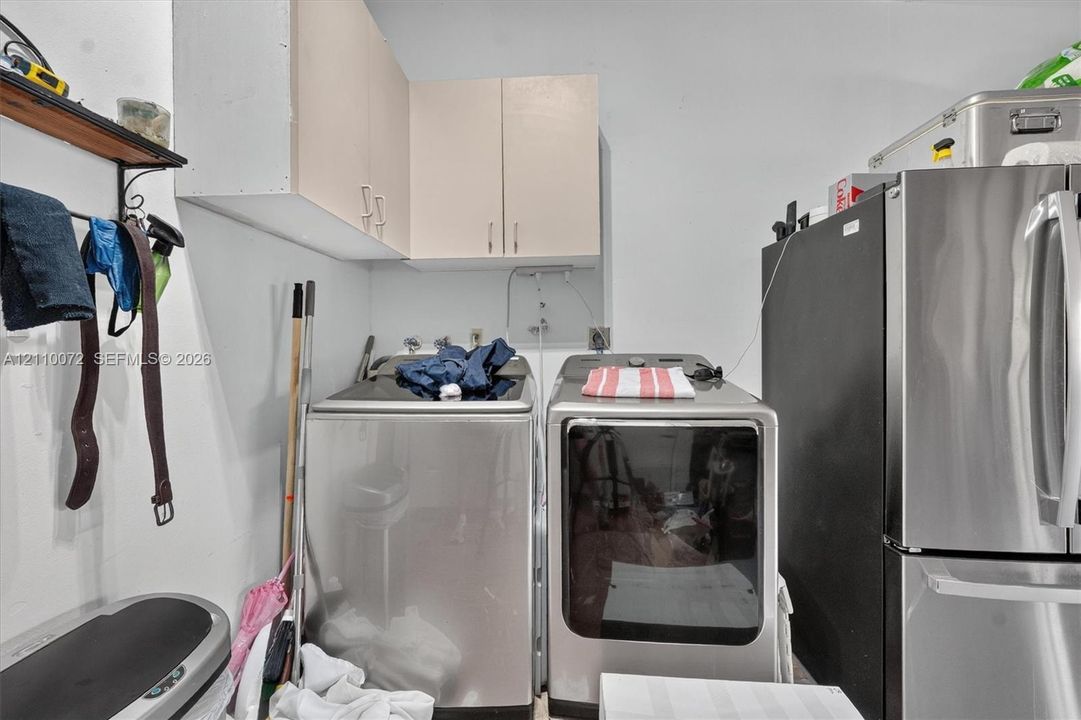 Laundry area featuring wall-mounted upper cabinetry and stainless steel appliance hookups