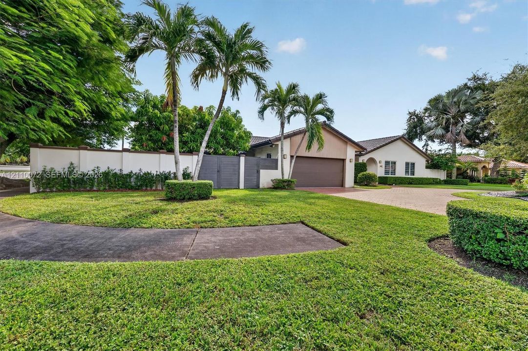 Single-story exterior featuring a paver driveway, an attached garage, and a solid perimeter privacy wall with gated entry