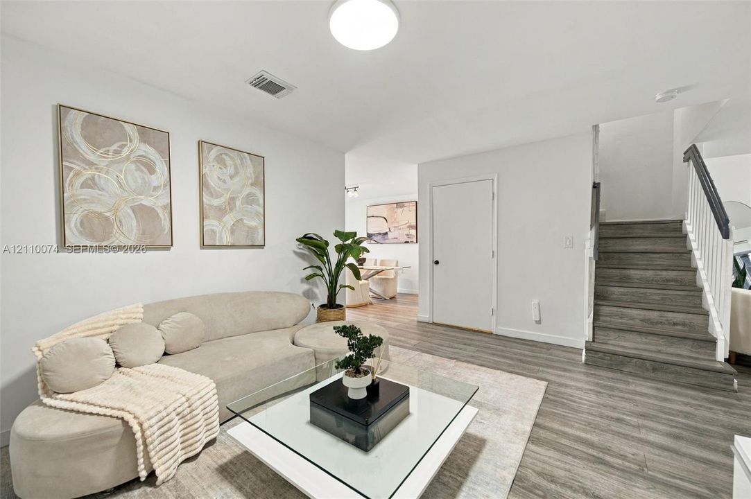 Interior featuring wood-finish flooring, staircase with a white balustrade, and a flush-mount ceiling fixture